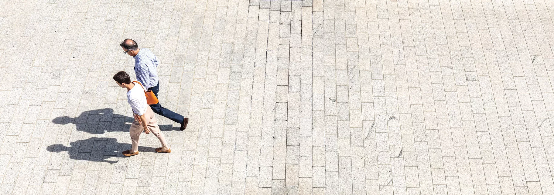 Two smartly-dressed people walking through campus on a sunny day